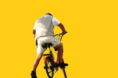 Man riding bicycle against yellow background