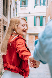 Couple holding hands while standing against buildings