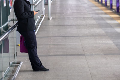 Low section of man using phone at airport