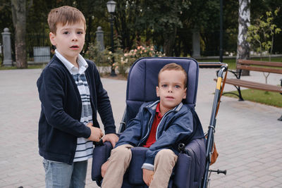 Family with cerebral palsy child on special wheelchair walking outdoors. integration and