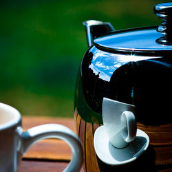 Reflection of cup and saucer on teapot