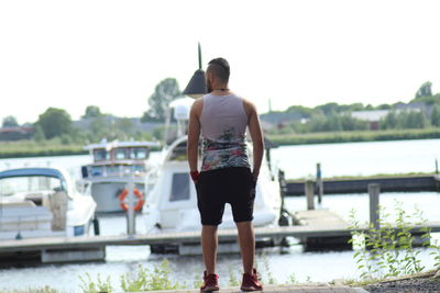 Rear view of man standing on riverbank against sky