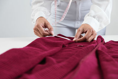 Midsection of fashion designer measuring cloth