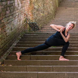 Young woman doing yoga on staircase