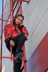 Smiling girl with african braids on a red metal ladder