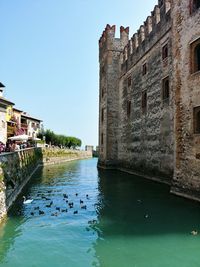 Canal amidst buildings against clear sky