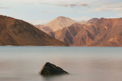 Scenic view of lake by mountains against sky