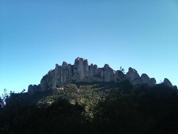 Low angle view of rocks against clear blue sky