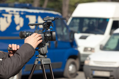 Close-up of hands operating camera on tripod