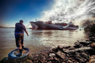 Rear view of man in sea against sky