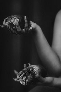 Cropped hands of woman holding meats against black background