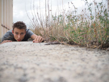 Portrait of young man lying on footpath