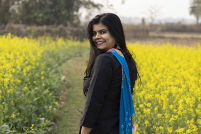 Portrait of smiling young woman standing on field