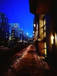Illuminated street amidst buildings in city at night