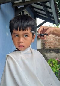 Cropped hand of hairdresser cutting boys hair outdoors