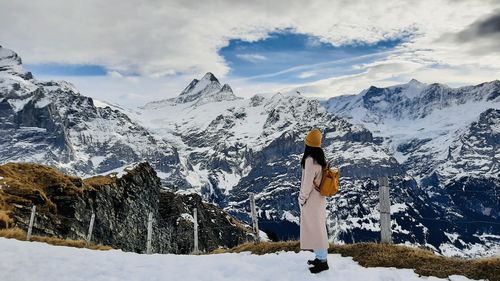 Rear view of woman standing on snowcapped mountains