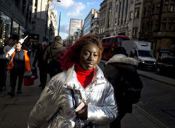 Portrait of young woman standing on city street