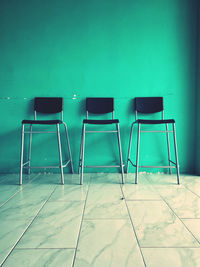 Empty chairs against tiled wall