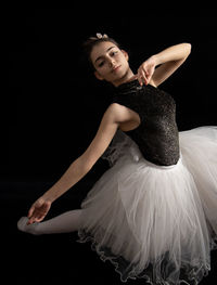 Portrait of woman dancing against black background