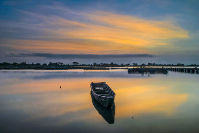 Abandoned boat on lake during sunset