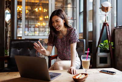 Young woman using mobile phone while sitting at cafe