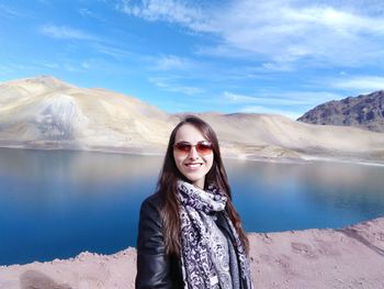 Young woman standing by lake against mountains