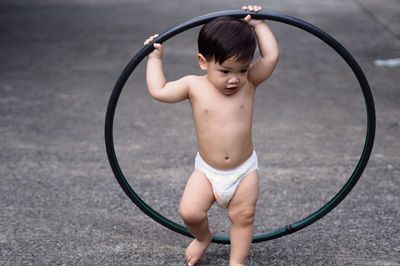 Full length of shirtless baby boy playing on street