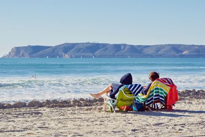 Rear view of people sitting on beach