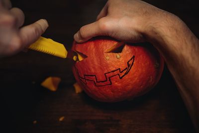 Jack's halloween pumpkin. man's hands carving mouth with paper knife. image with selective focus