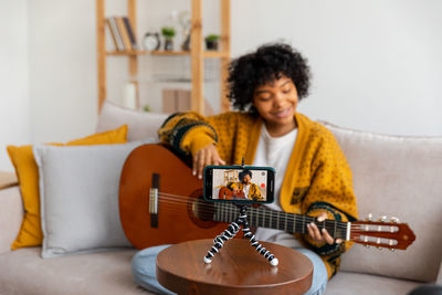 Young woman playing guitar at home