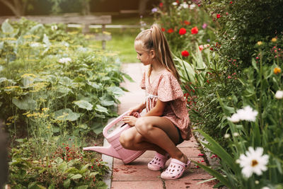 Full length of woman sitting by plants