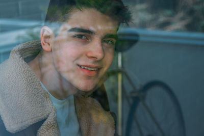 Portrait of male teenager behind window pane