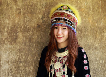 Portrait of smiling woman in traditional clothing against wall