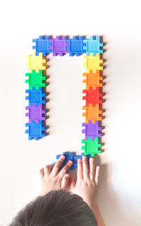 Close-up of boy wearing multi colored pencils against white background