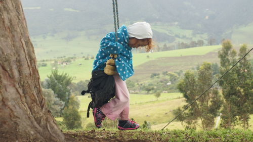 Full length of boy standing on field against mountain