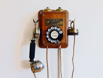 Close-up of old telephone booth against wall