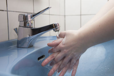 Close-up of person cleaning hands in bathroom