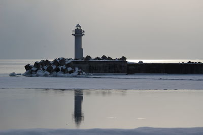 Lighthouse by sea against sky