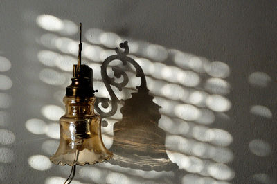 Close-up of electric lamp on table against wall