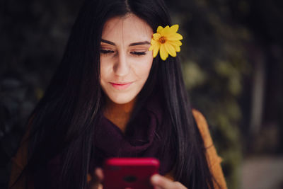 Close-up of woman taking selfie wearing flower in hair standing outdoors