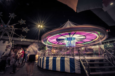 Illuminated ferris wheel in city at night