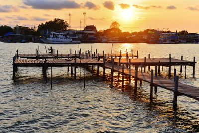 Wooden bridge extended into the river and sunset background