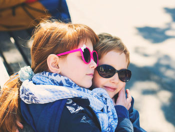 Siblings wearing sunglasses while embracing outdoors