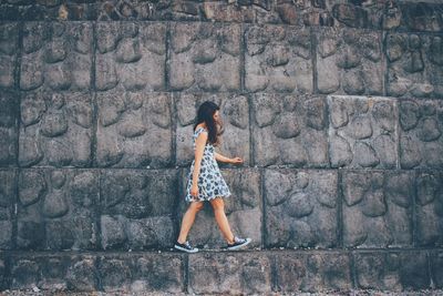 Full length of woman walking against wall