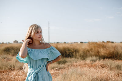 Teenage girl wearing dress standing on land against sky