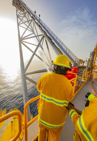 Low angle view of men working against sky