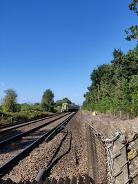 Train on railroad track against clear blue sky