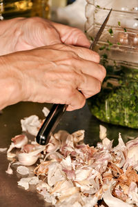 Peeling garlic with a knife to prepare a garlic and parsley sauce.