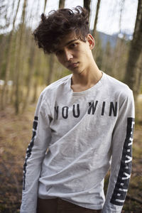 Portrait of young man standing at forest