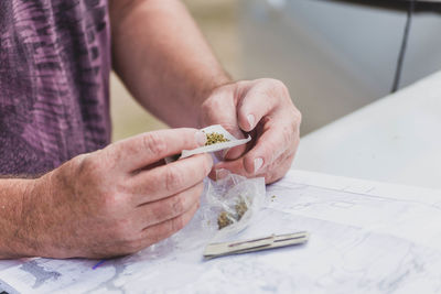 Close-up of man rolling marijuana joint